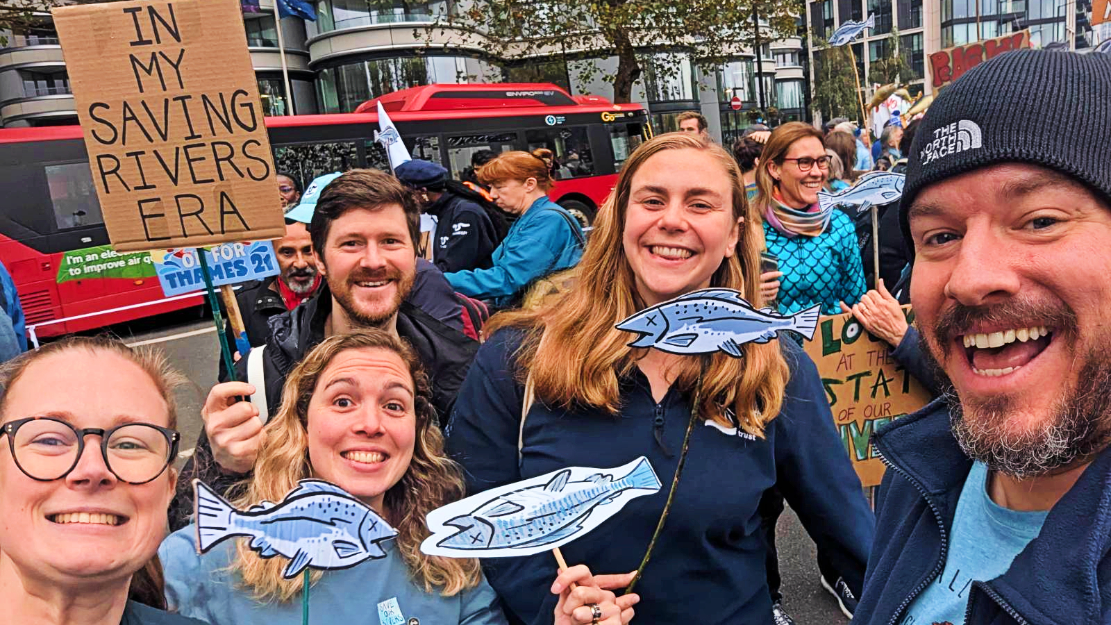 A gathering of individuals showcasing signs and holding fish, emphasizing community engagement and environmental awareness.